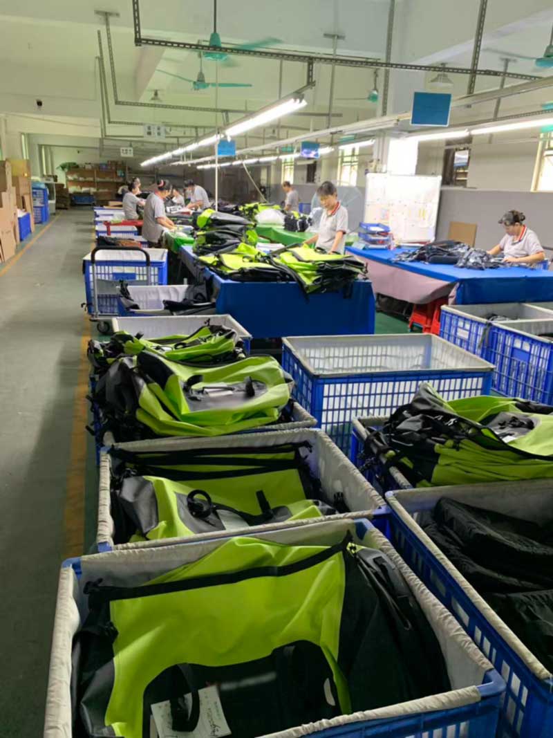Wide view of the assembly area with rows of trolleys holding partially finished waterproof bags
